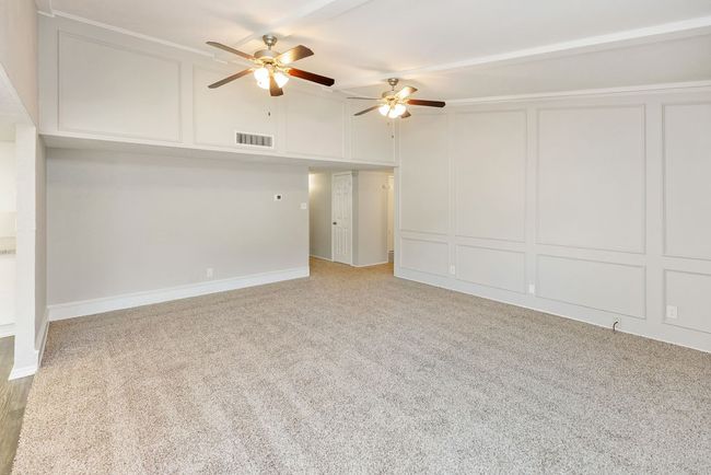 Empty room featuring a ceiling fan, a decorative wall, light colored carpet, and visible vents | Image 9