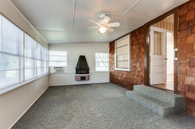 Unfurnished sunroom featuring a wood stove and cooling unit | Image 16
