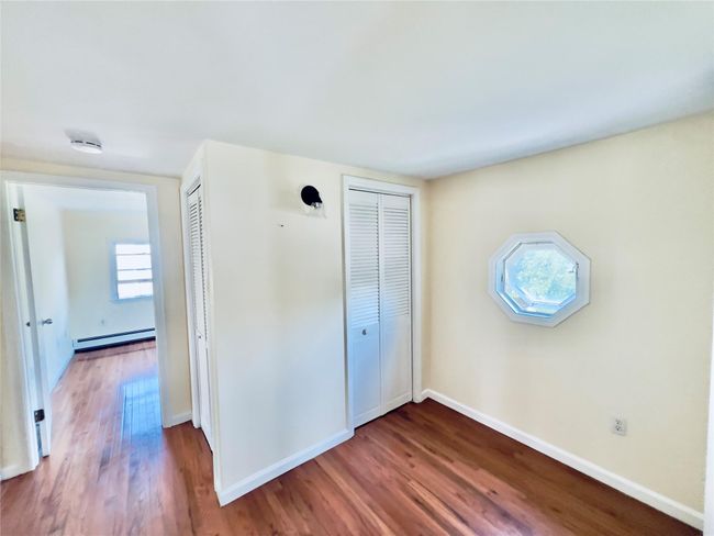 Unfurnished bedroom with wood finished floors and baseboard heating | Image 18
