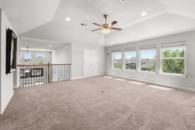 Large game room with vaulted ceiling, ceiling fan, and a healthy amount of sunlight and closet for storage. | Image 24