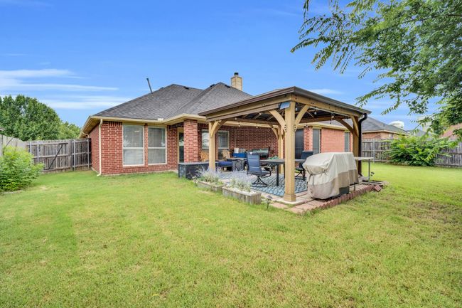 Back of property featuring brick siding, a chimney, a fenced backyard, and a patio | Image 35