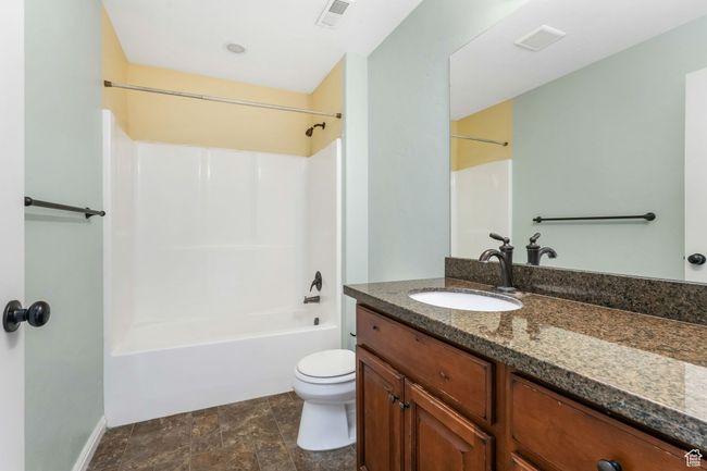 Full bathroom featuring visible vents, stone finish flooring, toilet, vanity, and shower / bath combination | Image 9