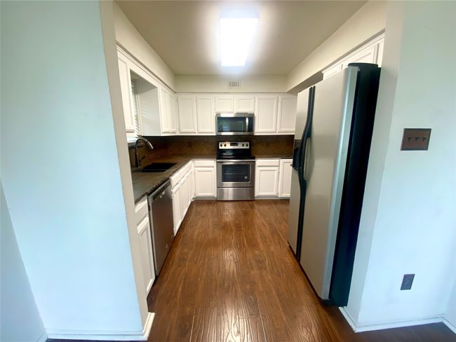 Kitchen featuring stainless steel appliances, decorative backsplash, and white cabinets | Image 7