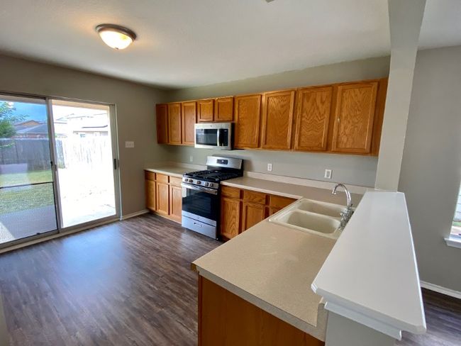 Kitchen featuring stainless steel appliances, dark wood-style floors, brown cabinetry, and plenty of natural light | Image 12
