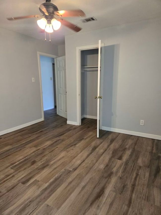 Unfurnished bedroom with dark wood-style floors, a closet, and a ceiling fan | Image 21