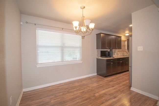 Kitchen with dark brown cabinetry, a chandelier, wood finished floors, and baseboards | Image 7