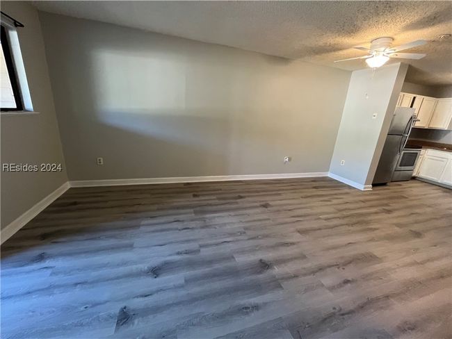 Empty room with a textured ceiling, hardwood / wood-style flooring, and ceiling fan | Image 14