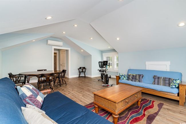 Living room featuring wood finished floors, a wall unit AC, baseboards, lofted ceiling, and recessed lighting | Image 26