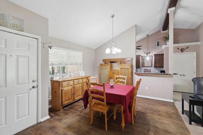 Dining space featuring high vaulted ceiling, visible vents, dark wood-style floors, and a notable chandelier | Image 4