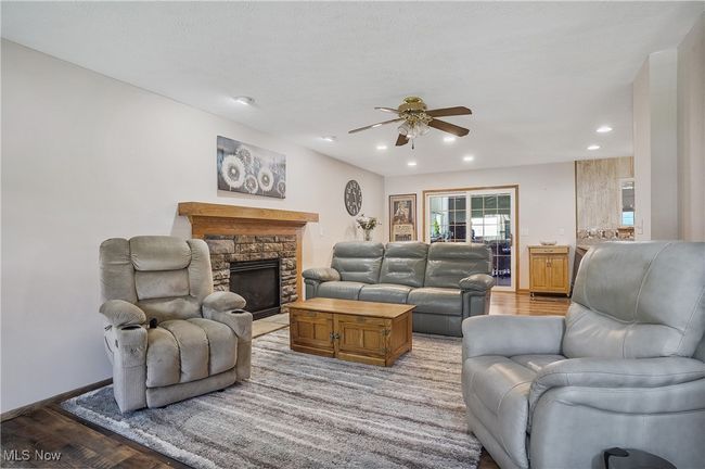 Living area with recessed lighting, light wood-style flooring, a stone fireplace, baseboards, and a ceiling fan | Image 7
