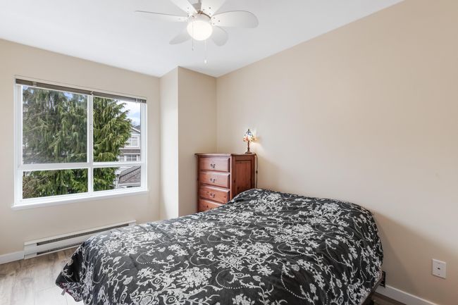 Bedroom featuring a baseboard radiator, baseboards, a ceiling fan, and wood finished floors | Image 22