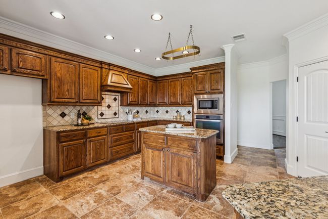 Kitchen featuring stainless steel appliances, crown molding, decorative backsplash and an island | Image 12
