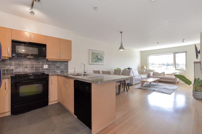 Kitchen with black appliances, a peninsula, open floor plan, decorative backsplash, and pendant lighting | Image 6