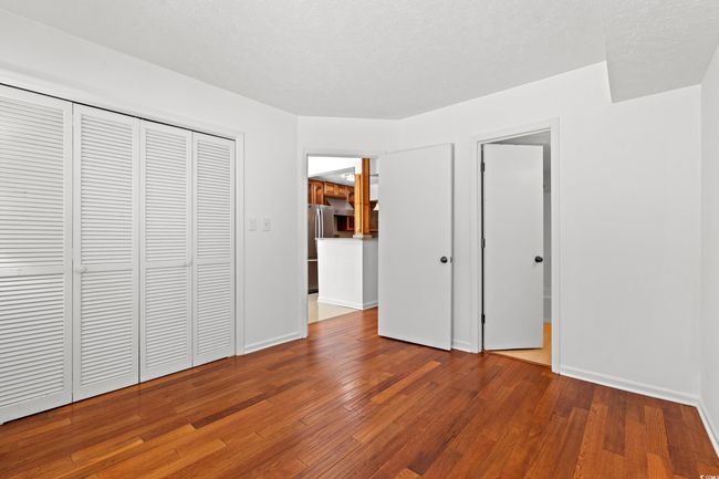 Unfurnished bedroom featuring wood finished floors, freestanding refrigerator, and a closet | Image 20