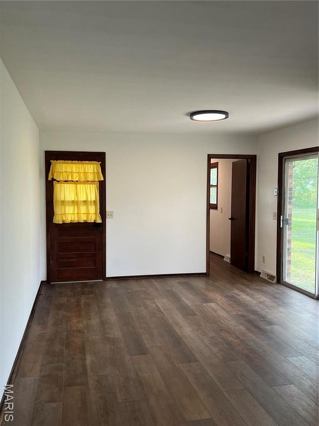 Empty room with baseboards, visible vents, and dark wood-type flooring | Image 16