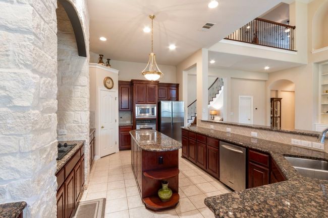 Kitchen with stainless steel appliances, a sink, open shelves, arched walkways, and dark stone countertops | Image 16