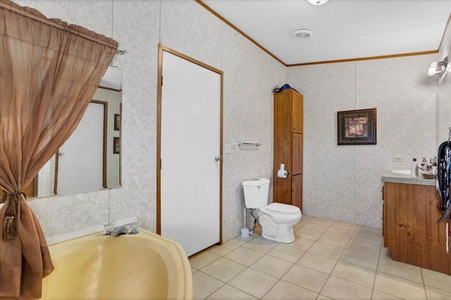 Bathroom with toilet, vanity, ornamental molding, and tile patterned floors | Image 16