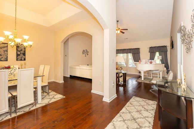 Dining space with arched walkways, wood-type flooring, baseboards, and ceiling fan with notable chandelier | Image 6
