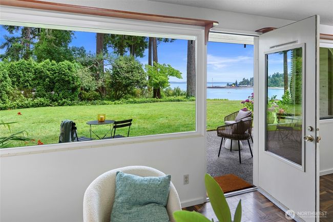 Living room door opens to the patio and lush green grass common area | Image 8