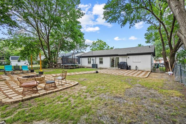View of yard featuring a trampoline, a patio, an outdoor fire pit, and central air condition unit | Image 36