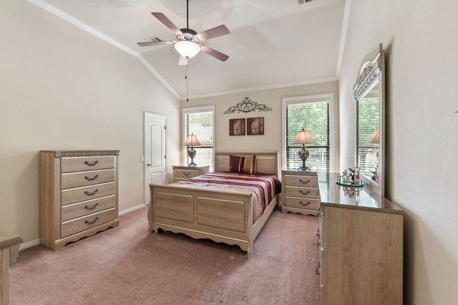 Bedroom with crown molding, light colored carpet, lofted ceiling, and ceiling fan | Image 23