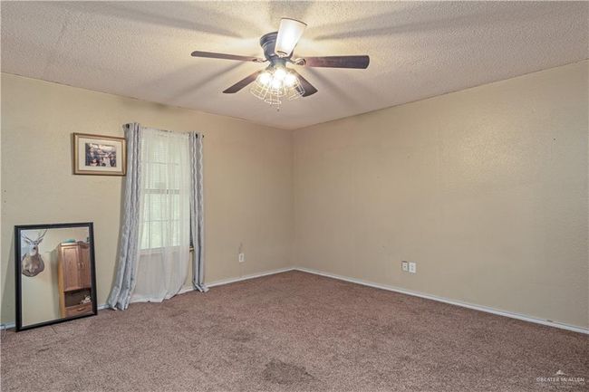 Empty room featuring carpet floors, a ceiling fan, a textured ceiling, and baseboards | Image 17