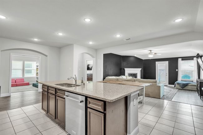 Kitchen with arched walkways, stainless steel dishwasher, ceiling fan, light tile patterned floors, and open floor plan | Image 8