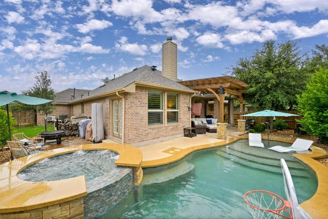 View of swimming pool with a pergola, a patio area, an outdoor living space with a fire pit, and a pool with connected hot tub | Image 31
