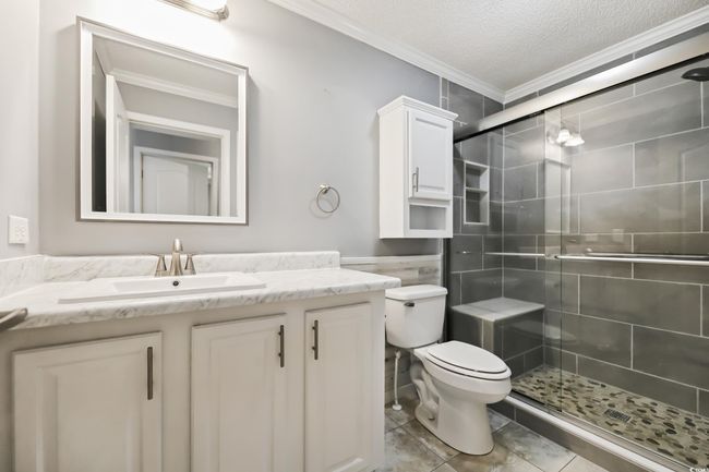 Full bath with crown molding, vanity, a shower stall, toilet, and a textured ceiling | Image 24