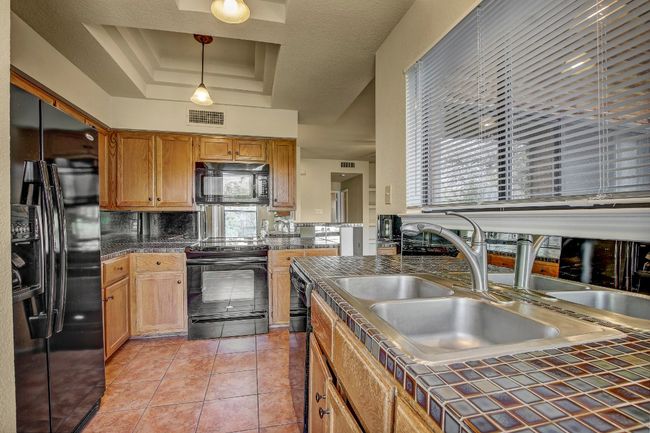 Kitchen with Black appliances, tile counters and nice storage | Image 11