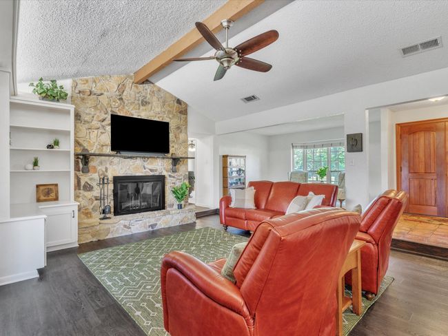 Living room with a textured ceiling, ceiling fan, a fireplace, and wood finished floors | Image 10