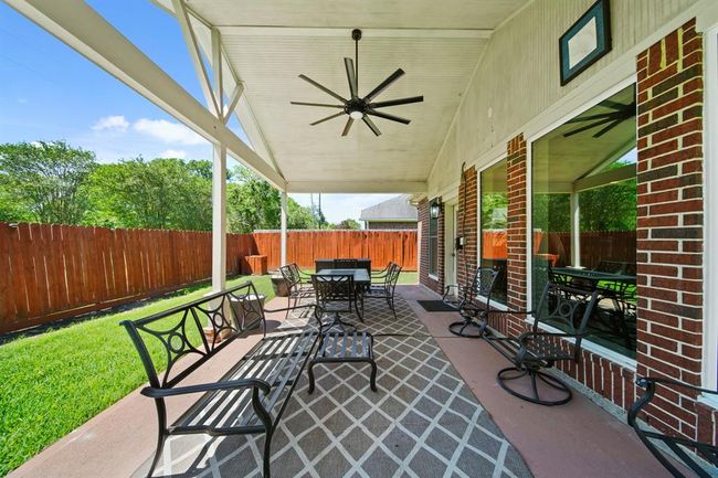 Enjoy your mornings or unwind in the evening beneath the expansive covered patio featuring a soaring ceiling and ceiling fan for added comfort. | Image 45