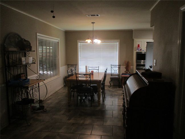 Dining room featuring crown molding, dark tile patterned flooring, and a notable chandelier | Image 13