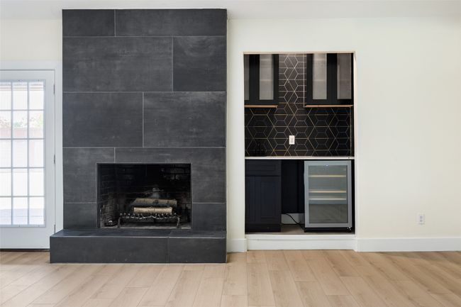 Detailed view of beverage cooler, wood finished floors, and a large fireplace | Image 7
