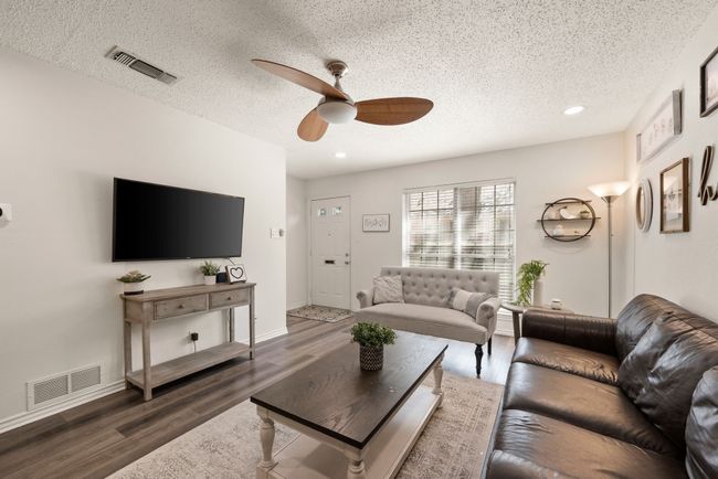 Living room with a textured ceiling, wood finished floors, visible vents, and a ceiling fan | Image 5