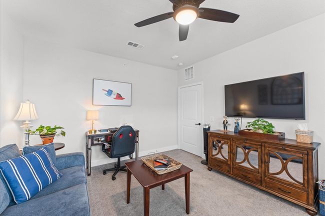 Currently set up as a home office and den, this multi-purpose room offers space for a large TV, ample storage, and comfort for work or leisure. | Image 18