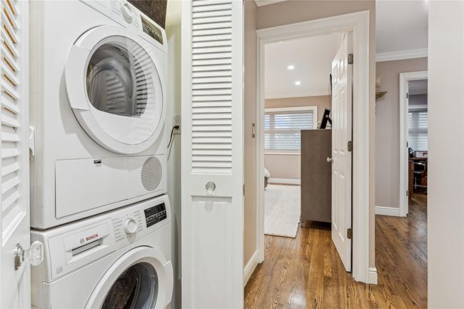 Laundry area featuring crown molding, stacked washer / drying machine, and wood-type flooring | Image 19