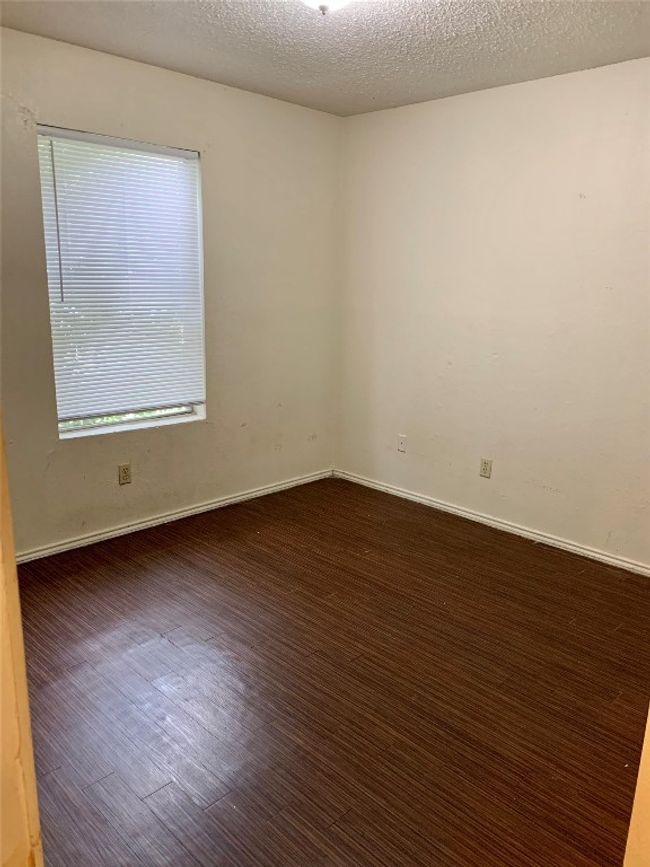 Unfurnished room featuring a textured ceiling, baseboards, and wood finished floors | Image 9