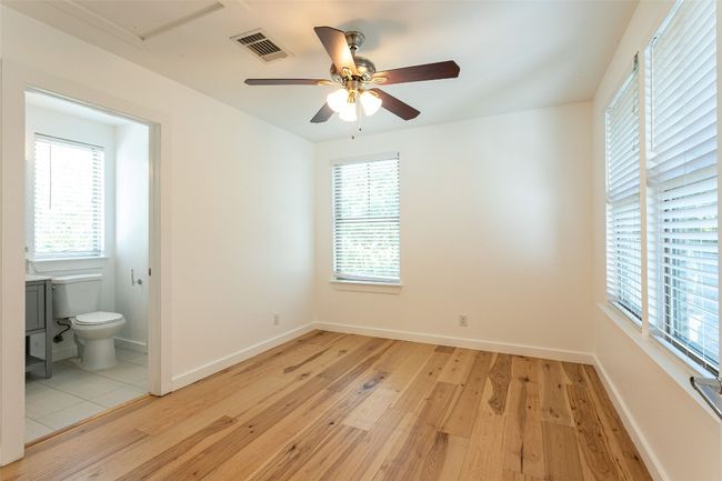 Unfurnished bedroom with light wood-style floors, multiple windows, and connected bathroom | Image 16
