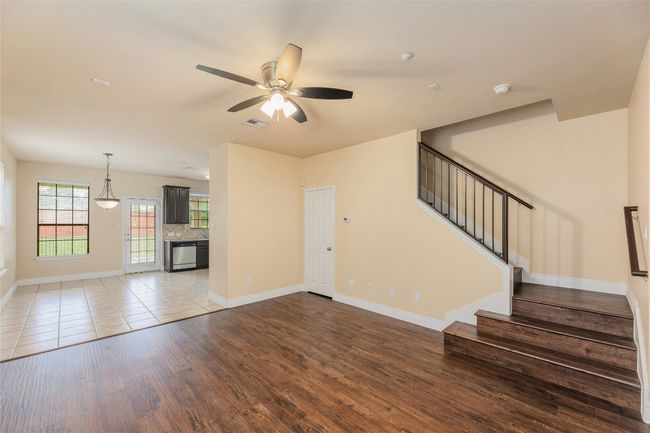 Unfurnished living room with wood finished floors, a ceiling fan, and stairs | Image 5