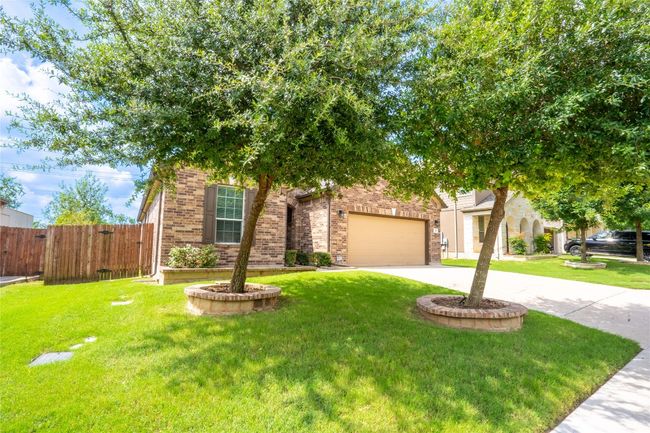 View of property hidden behind natural elements with concrete driveway, brick siding, and a garage | Image 34