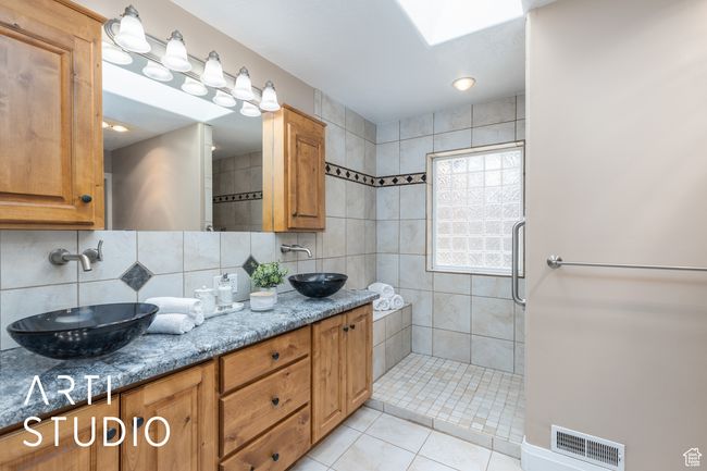Bathroom with a sink, visible vents, tasteful backsplash, and tiled shower | Image 6