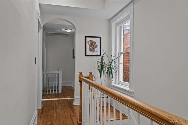 Hall with hardwood / wood-style flooring, arched walkways, baseboards, and an upstairs landing | Image 23