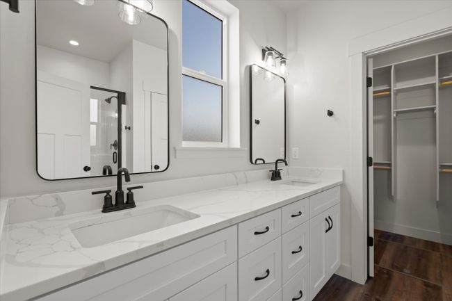 Bathroom featuring a sink, a walk in closet, wood finished floors, and double vanity | Image 16