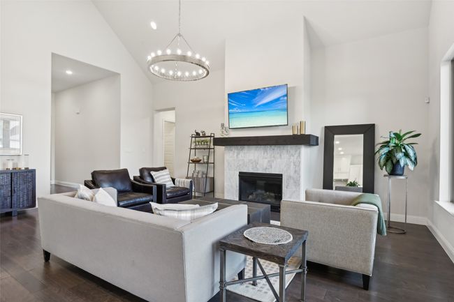 Living area with high vaulted ceiling, a chandelier, dark wood finished floors, a tile fireplace, and recessed lighting | Image 10