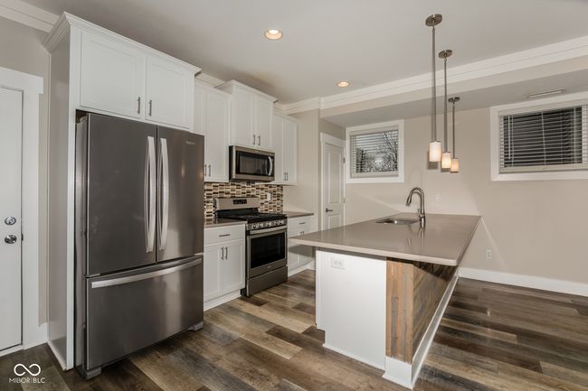kitchen with stainless steel appliances, dark wood-style floors, decorative backsplash, and white cabinetry | Image 12