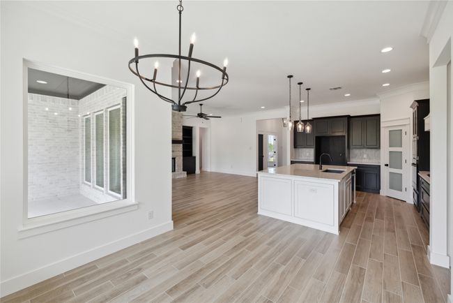 Kitchen featuring a fireplace, an island with sink, sink, decorative backsplash, and hanging light fixtures | Image 21