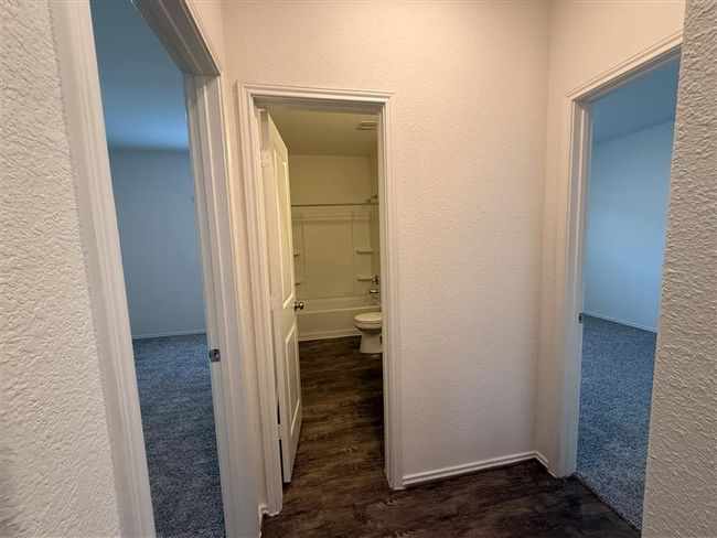 Hall with wood finished floors and a textured wall | Image 15