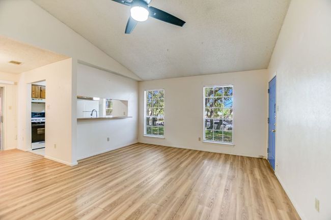 Unfurnished room featuring light wood-style flooring, ceiling fan, lofted ceiling, and baseboards | Image 5