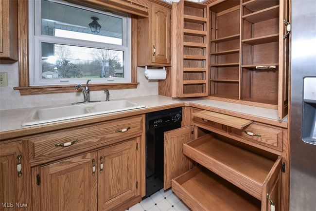 Kitchen featuring a sink, black dishwasher, brown cabinets, open shelves, and light countertops | Image 24